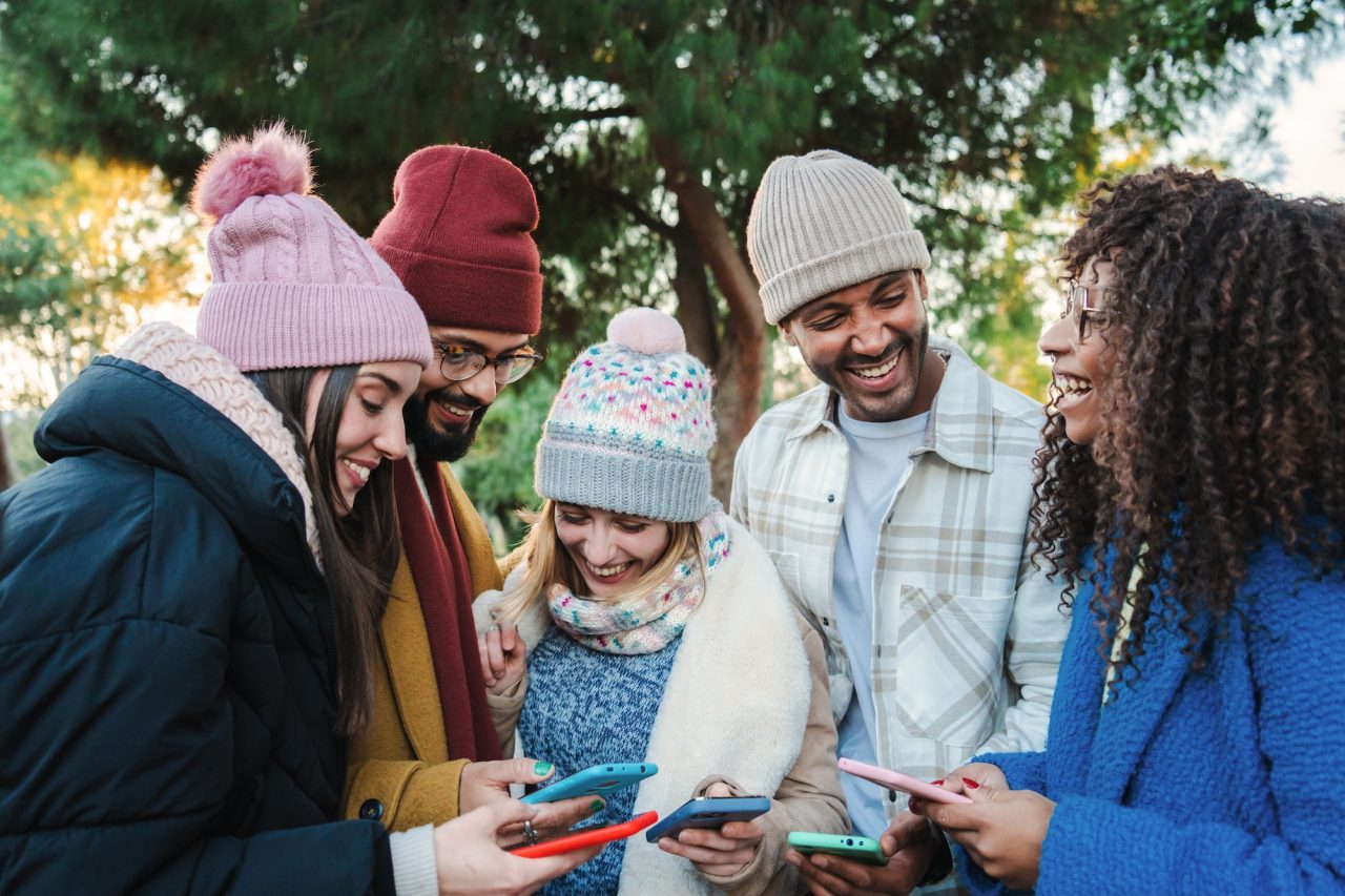 group-of-multiracial-young-friends-with-coats-and-hats-smiling-and-watching-the-social-media-with-a.jpg